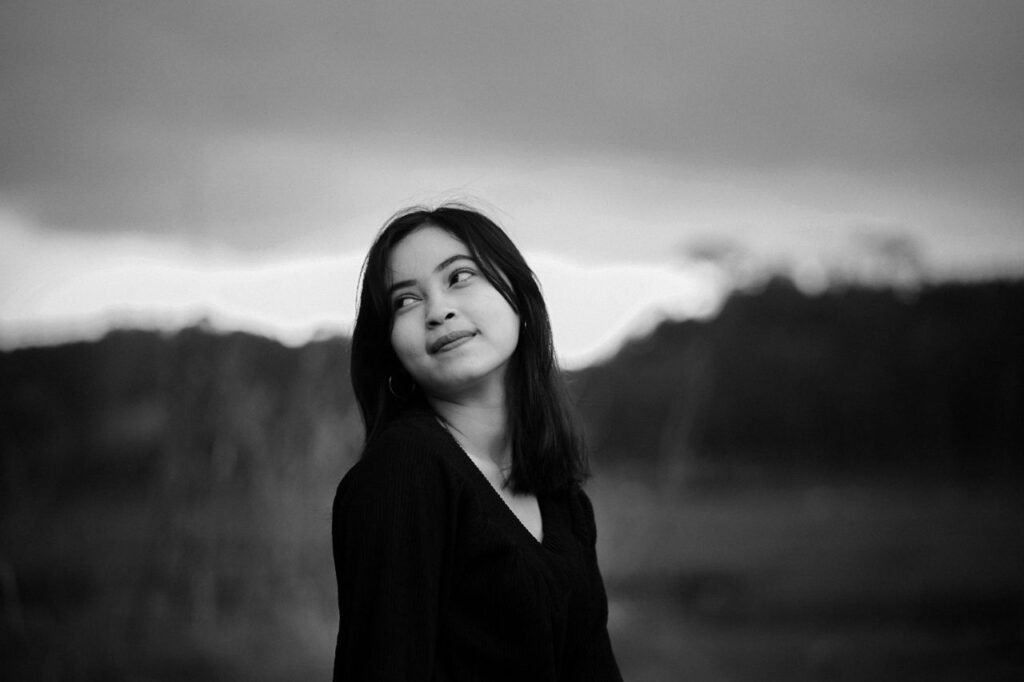 A captivating black and white portrait of a young woman looking upwards outdoors.